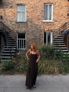 Woman in a long dark dress standing in a brick courtyard between two staircases