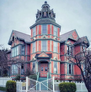 Pink Victorian house with turret tower and white picket fence