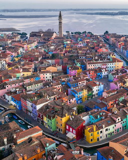 Aerial view of colorful houses on Burano island, Venice, with a bell tower and lagoon in the background