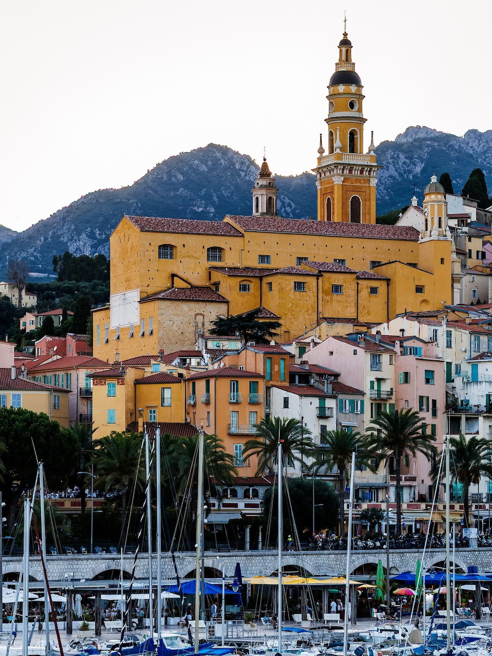 Menton old town with yellow church tower, colorful buildings, marina and mountains