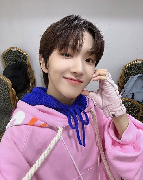 Young man in pink hoodie with blue collar smiling at camera in backstage setting