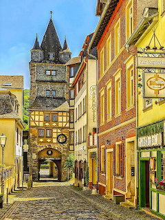 Cobblestone village street with colorful historic buildings and a stone tower in Germany