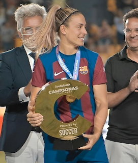 Alexia Putellas in an FC Barcelona jersey holding a trophy and wearing a medal on stage