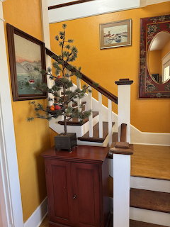 Bright yellow hallway interior with white staircase, wooden cabinet, and wall art