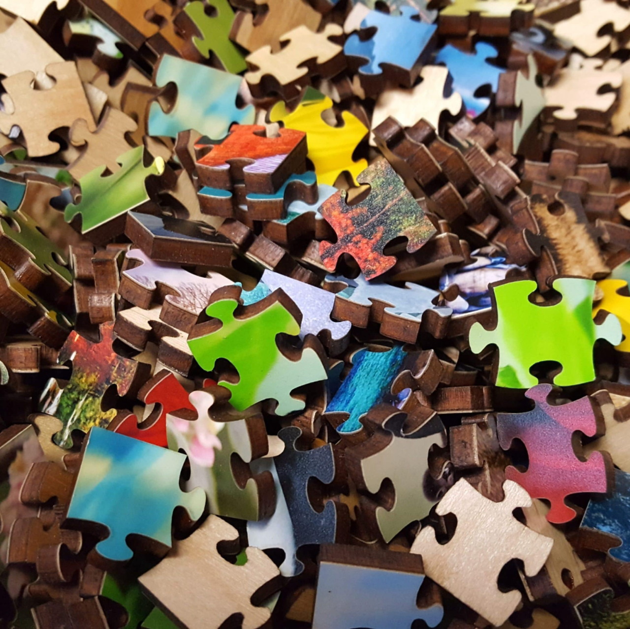 Close-up of scattered jigsaw puzzle pieces in a colorful mixed pile