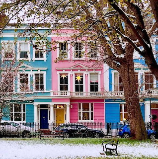 Colorful pastel row houses with snow on the ground and bare trees in a London street scene