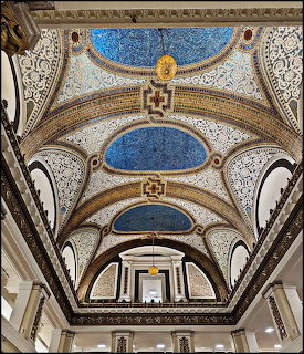 Looking up at ornate ceiling with blue mosaic arches, gold decorative trim, and classical architectural details