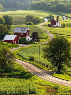Winding rural road through green farmland with red barns and silos in rolling hills of Lancaster County Pennsylvania