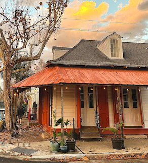 Historic corner building with red awning at sunset, bare trees against golden sky