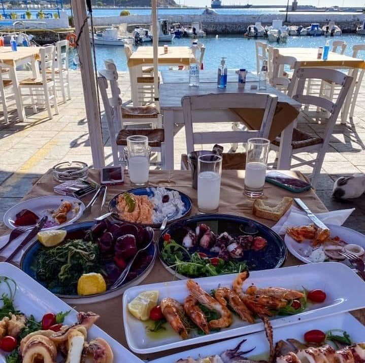 Colorful Greek seafood lunch with prawns, mussels and salads at seaside restaurant table with harbor view