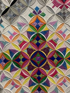 Colorful cathedral window quilt with geometric patchwork pattern in multiple vibrant colors