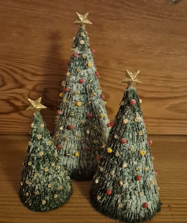 Three paper Christmas trees with gold stars on a wooden tabletop