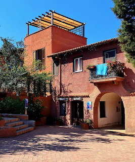 Red stucco Mediterranean house with pergola, arched doorway, and balcony in Capri, Italy