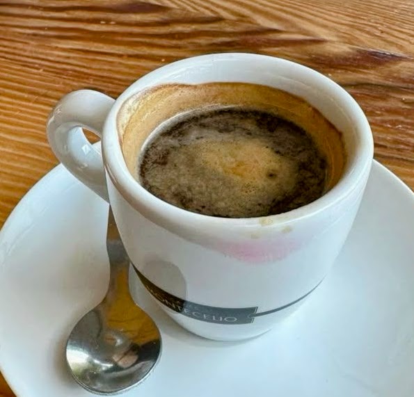 White coffee cup on a saucer with a spoon on a wooden table
