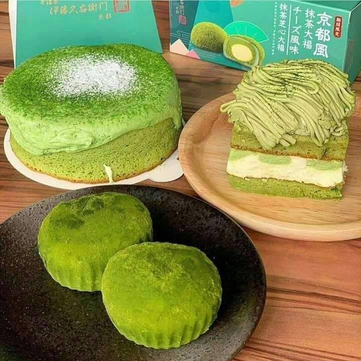 Green matcha desserts displayed on wooden plates and dark bowl, including layered cake and mochi