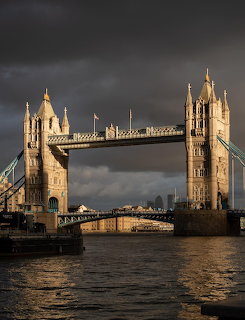 Tower Bridge over the River Thames in London with dark stormy clouds and golden light