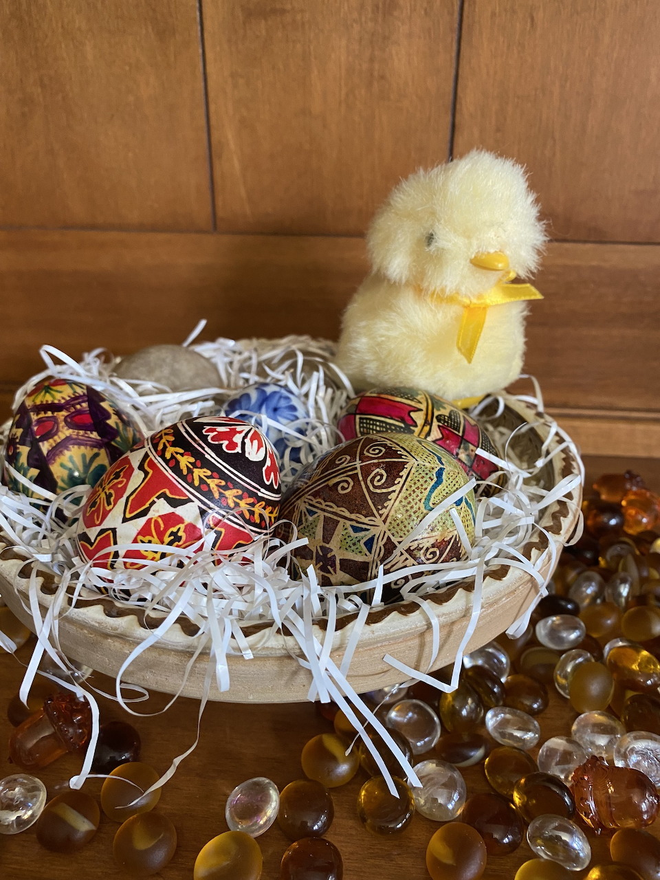 Basket with decorated eggs and a yellow chick on a wooden surface