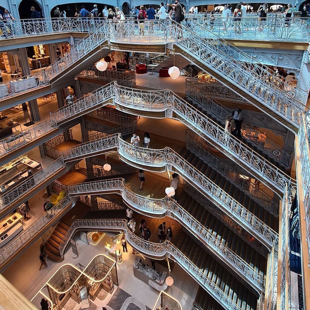 Ornate multi-story department store interior with white decorative balconies and classical architectural details