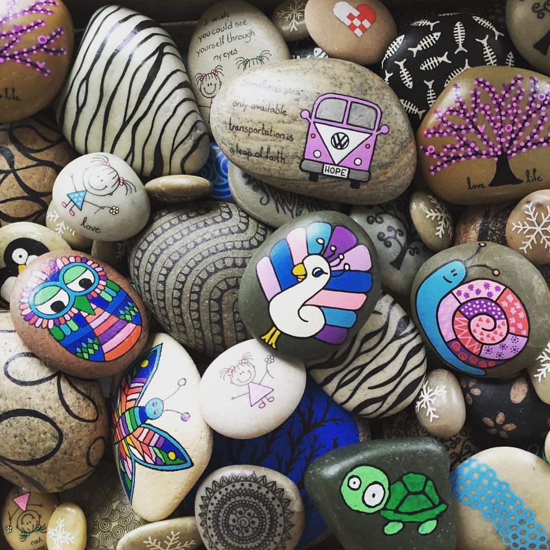 Colorful hand-painted pebbles with patterns, a bird, turtle, owl, and decorative designs