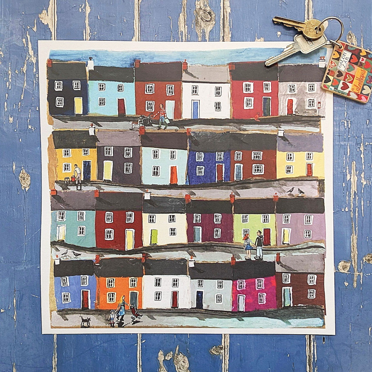 Painting of colorful row houses clipped to a distressed blue wooden background