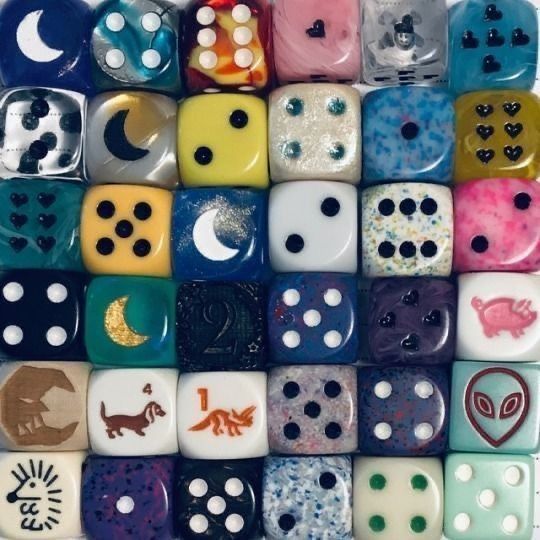 Close-up of colorful assorted dice arranged in a grid with painted symbols and dot patterns