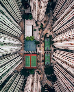 Aerial top-down view of dense Hong Kong skyscrapers surrounding a courtyard with sports courts