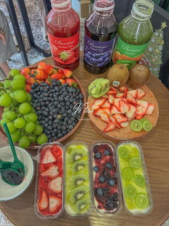 Colorful fruit platter with grapes, berries, kiwi, strawberries and juice bottles on wooden table