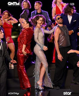 People in glamorous dresses posing on a dark stage during a fashion TV show
