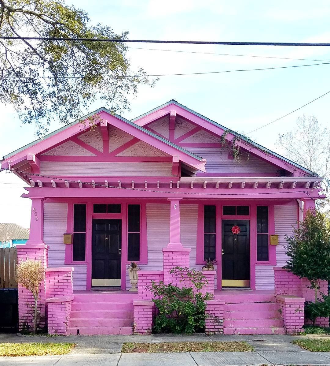 Bright pink craftsman style house with twin front doors and decorative gable trim