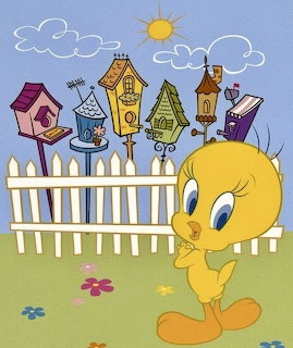Cartoon Tweety standing near a white fence with colorful birdhouses under a sunny sky