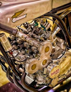 Close-up of a vintage Ducati DOHC racing motorcycle engine with gold frame and chrome components