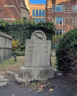 Weathered gravestone of Edgar Allan Poe in an old cemetery with fallen leaves