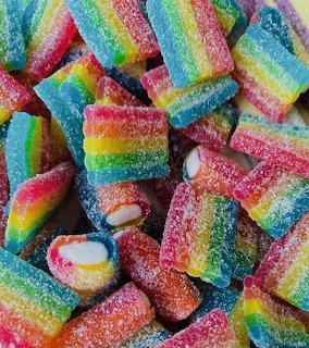 Pile of rainbow-striped sour gummy candies coated in sugar