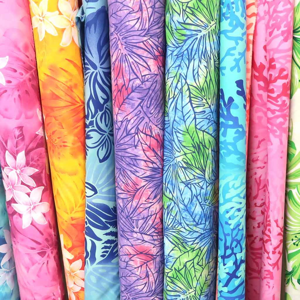 Colorful rolled fabric bolts with floral and tie-dye patterns in pink, yellow, blue, purple, and green