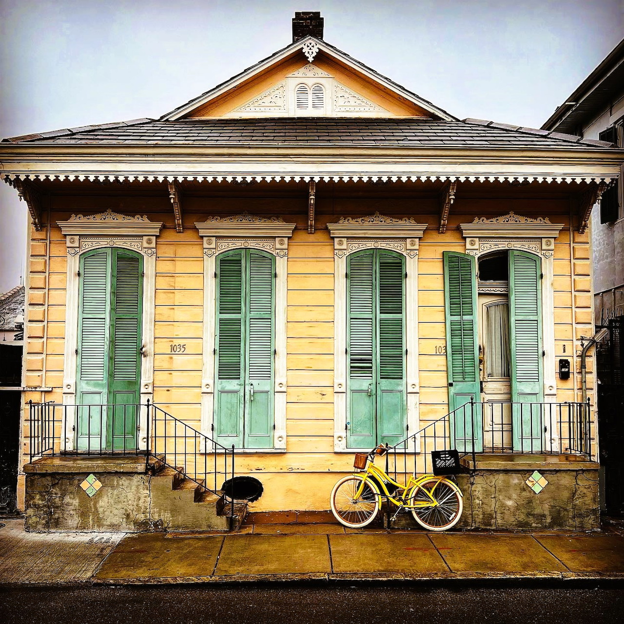 Yellow cottage with mint green shutters and bicycle in front