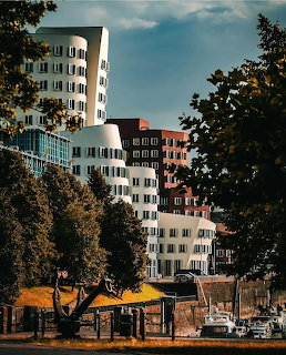 Modern white and red curved buildings in Düsseldorf with green trees and waterfront area