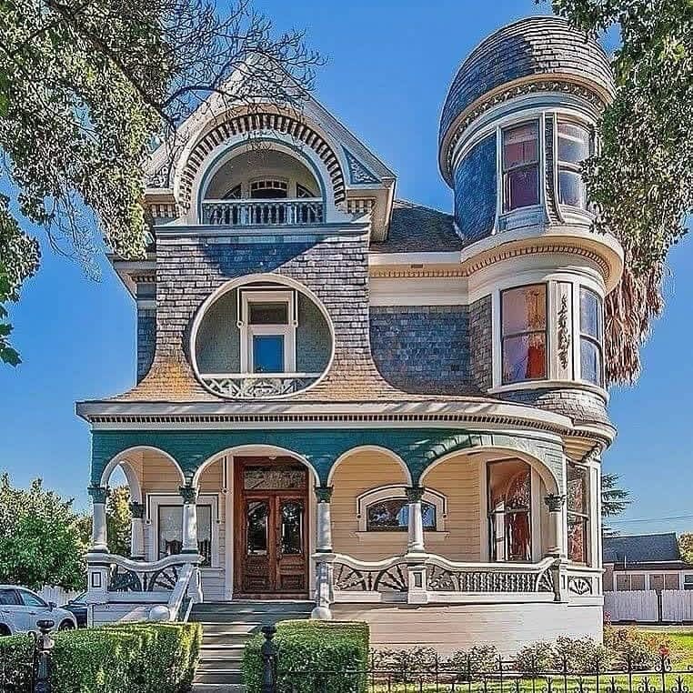 Colorful Victorian mansion with round turret, arched windows, and ornate porch details