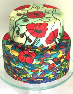 Two-tier cake with red flowers, vines, and colorful mosaic-style icing decoration