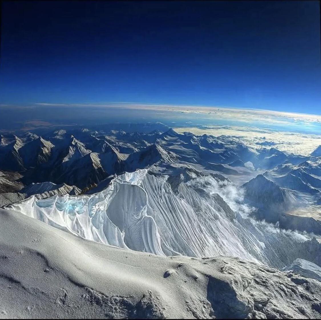Aerial view of snow-covered mountain peaks under clear blue sky
