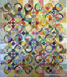 Colorful patchwork quilt with circular rings and geometric squares in various bright fabric patterns
