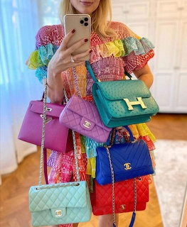 Woman holding multiple colorful quilted designer handbags in various bright colors