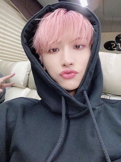 Young man with pink hair in black hoodie taking a selfie in a car with peace sign