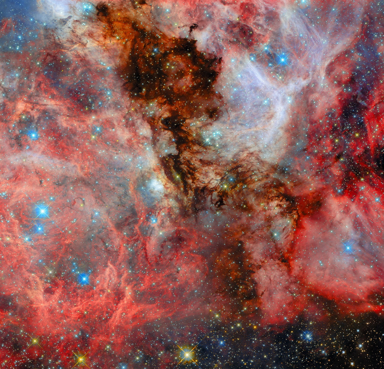 Colorful red nebula with dark dust lanes and bright blue stars in deep space