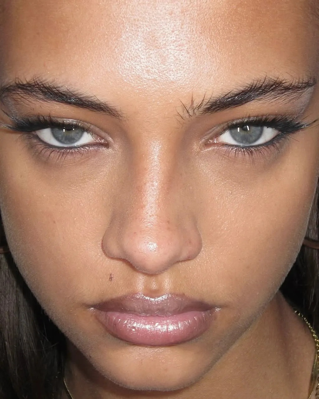 Close-up portrait of a blonde woman with glowing skin and detailed makeup