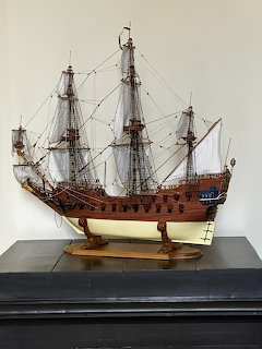 Detailed wooden model of a historic tall sailing ship with masts and rigging on a dark shelf