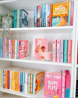 White bookshelf with colorful books, a candle, and a small art print