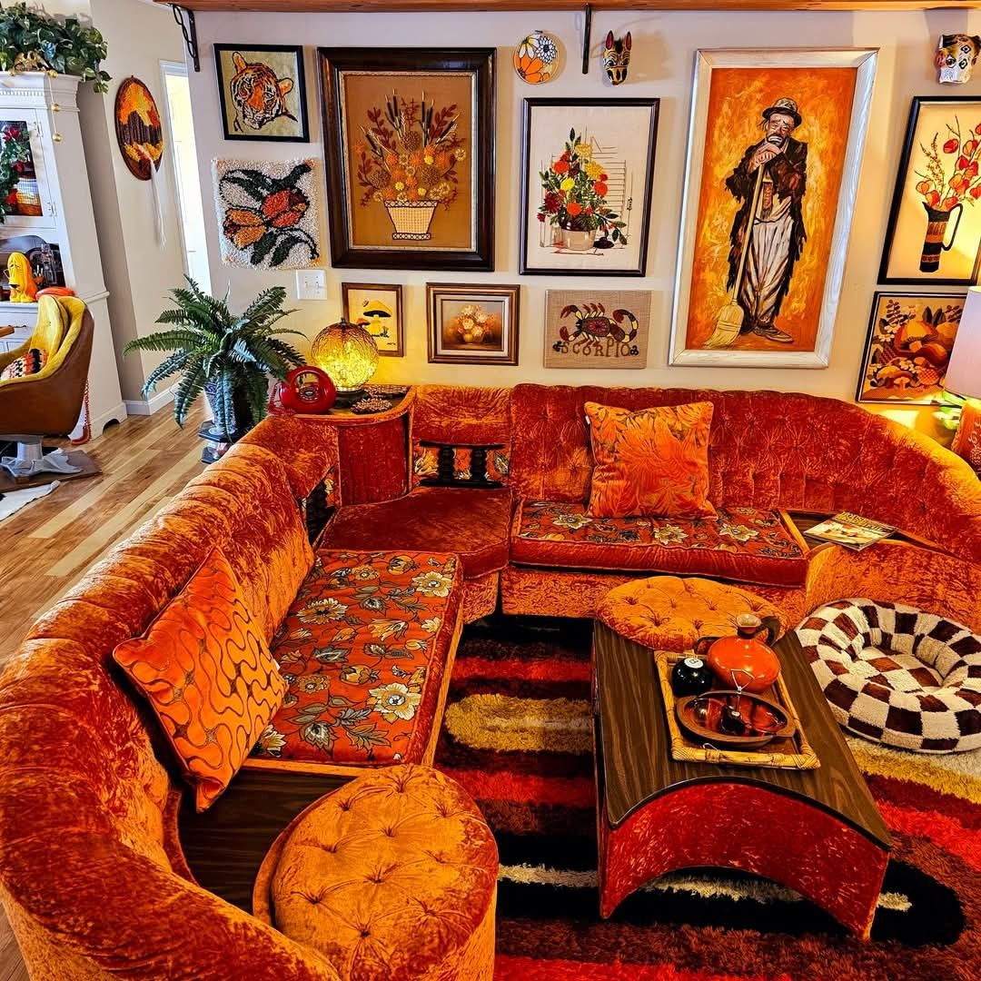 Colorful bohemian living room with a curved orange sofa, framed wall art, patterned rug, and coffee table