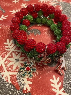 Red and green beaded Christmas wreath bracelet with snowflake charm on festive red background