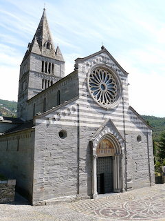 Stone facade of Basilica dei Fieschi with rose window, arched entrance, and bell tower