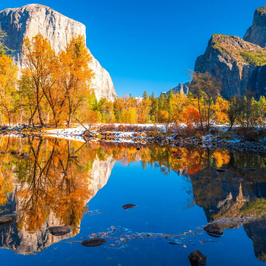 Autumn trees and granite cliffs reflected in calm water at Yosemite National Park